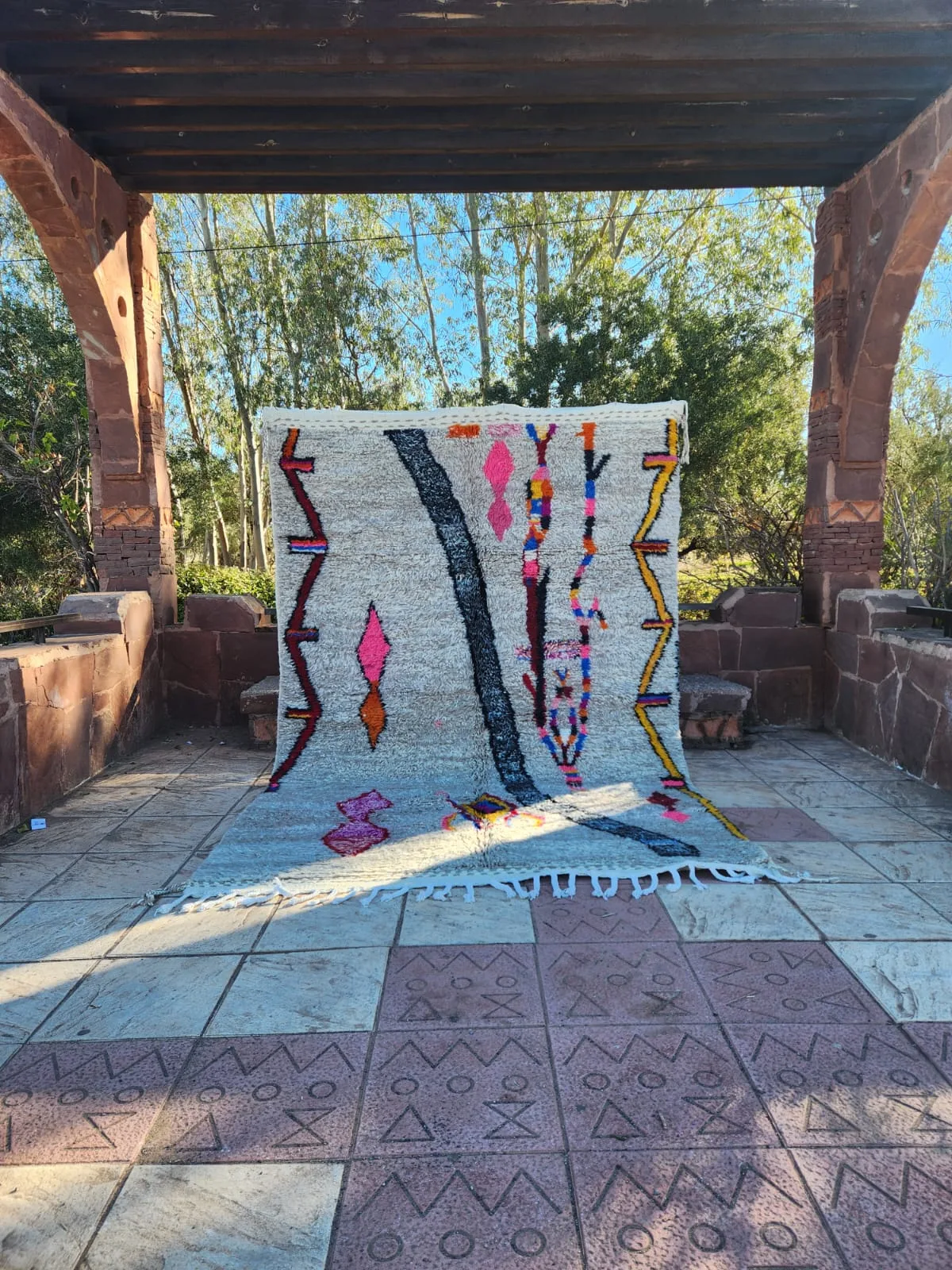 Colourful Azilal rug displayed in a terracotta archway with garden behind