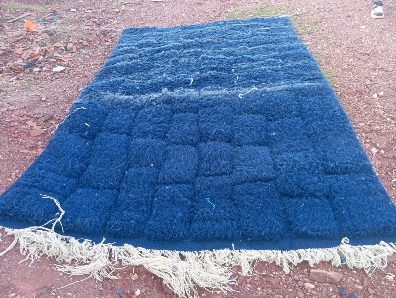 Handwoven Moroccan rug laid across rock in the Atlas Mountains