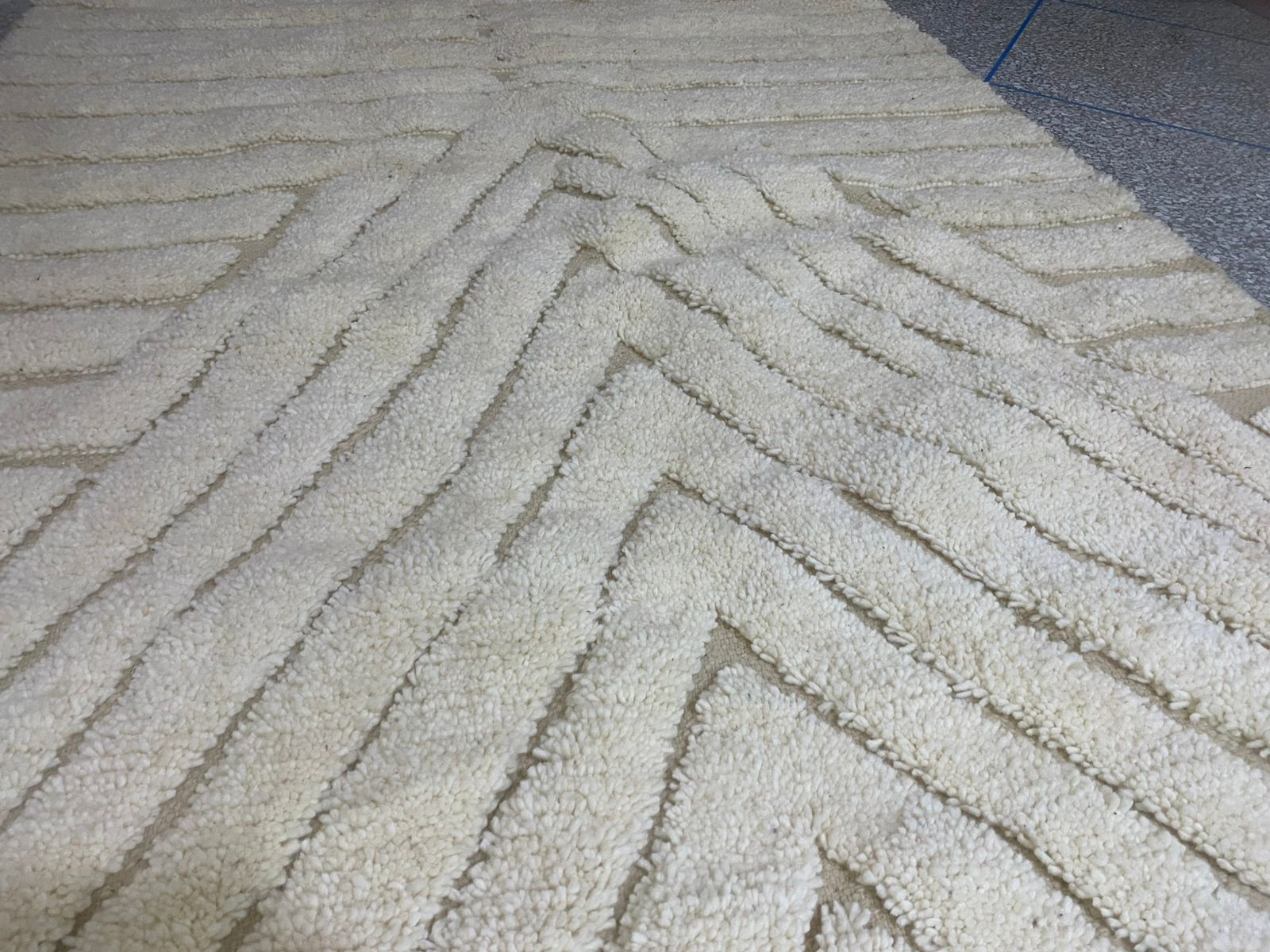 Close-up low-angle view across an ivory Moroccan rug with deep chevron pile, geometry receding into the distance