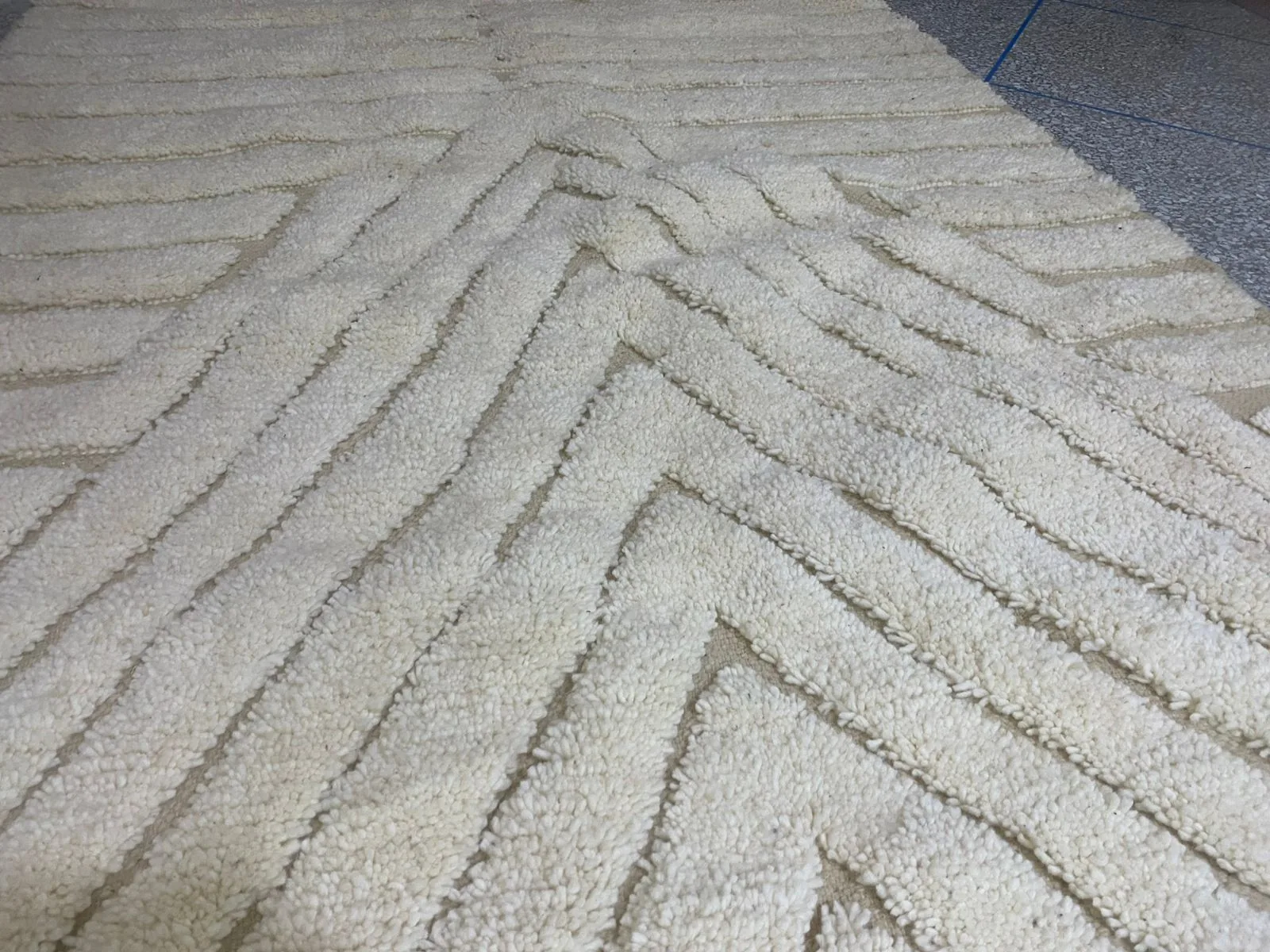 Close-up low-angle view across an ivory Moroccan rug with deep chevron pile, geometry receding into the distance