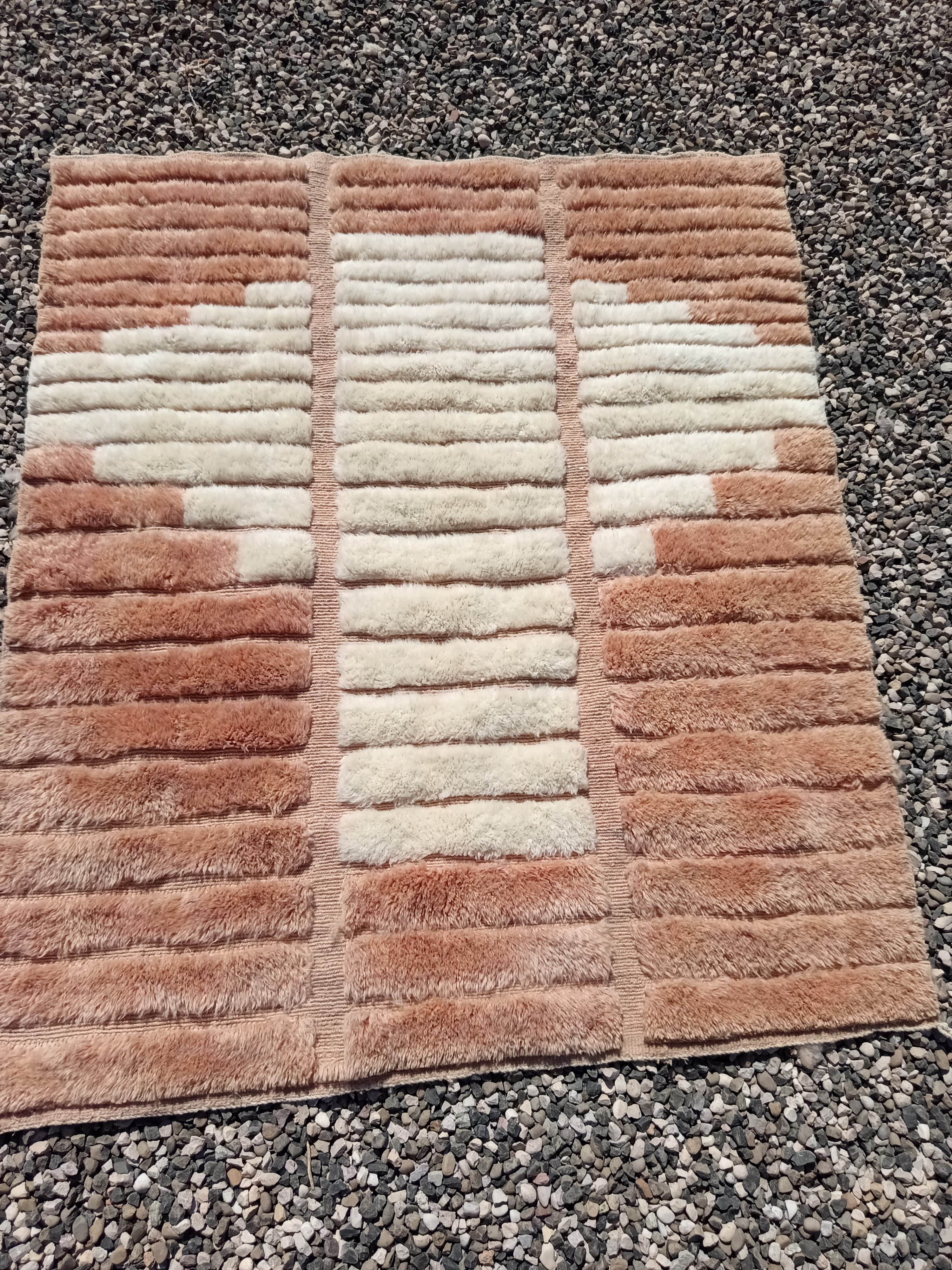 Caramel and ivory Boujaad rug with alternating horizontal bands in a cross composition, laid flat on gravel