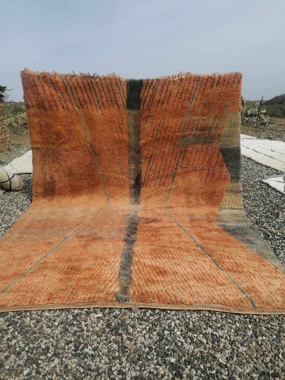 Large burnt orange Boujaad pile rug with broad grey abstract stripes, Atlas mountains backdrop