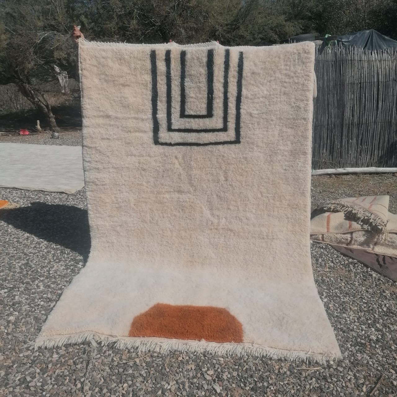 Ivory Moroccan rug with a single minimal black nested square arch motif and a small rust terracotta rectangle