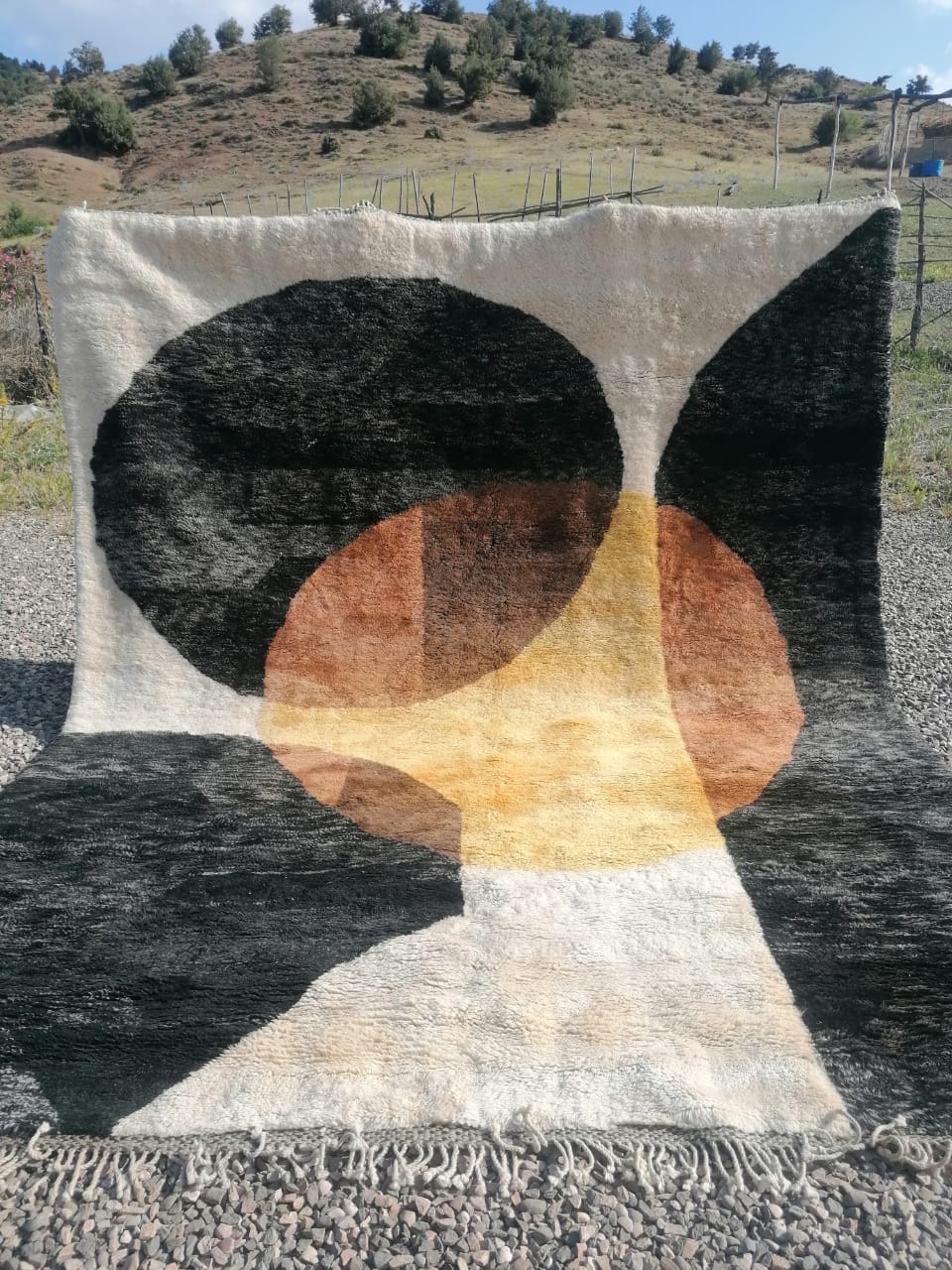 Moroccan rug with bold overlapping circles in charcoal, amber and terracotta on ivory