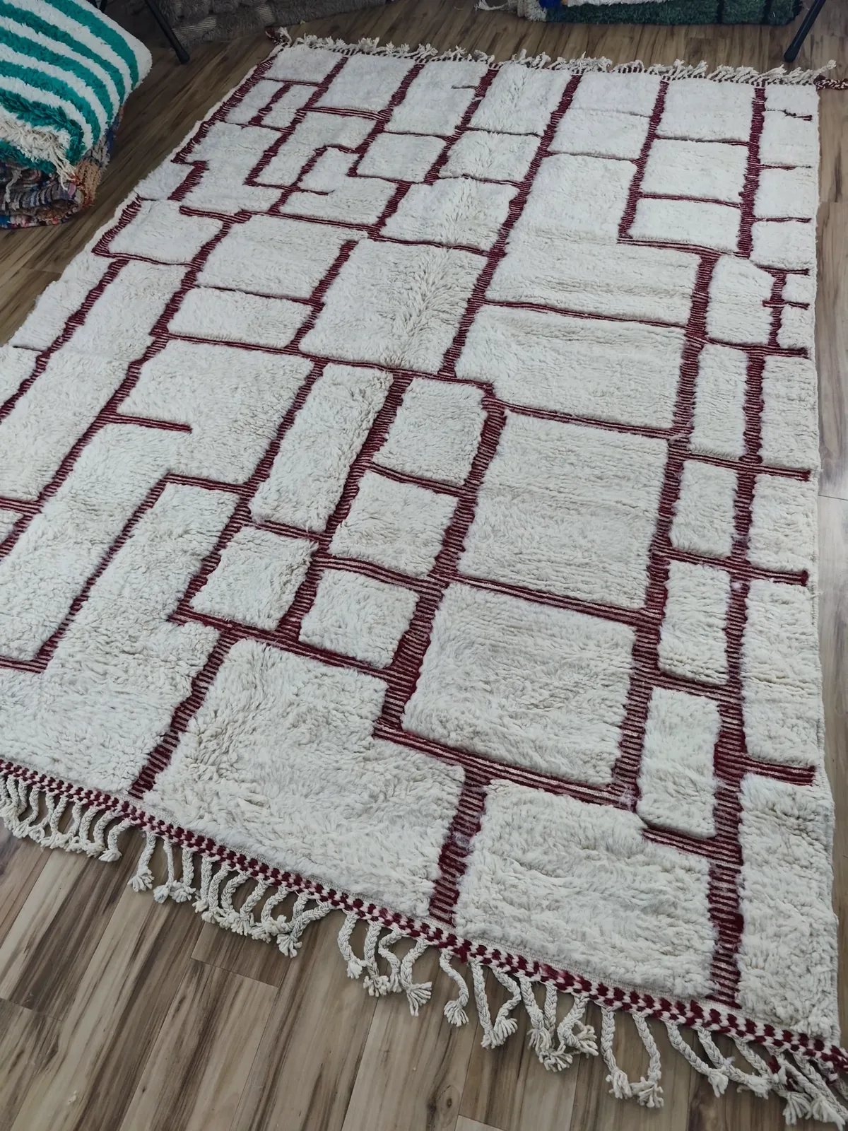 Ivory contemporary rug with burgundy rectangular grid pattern, hung in studio