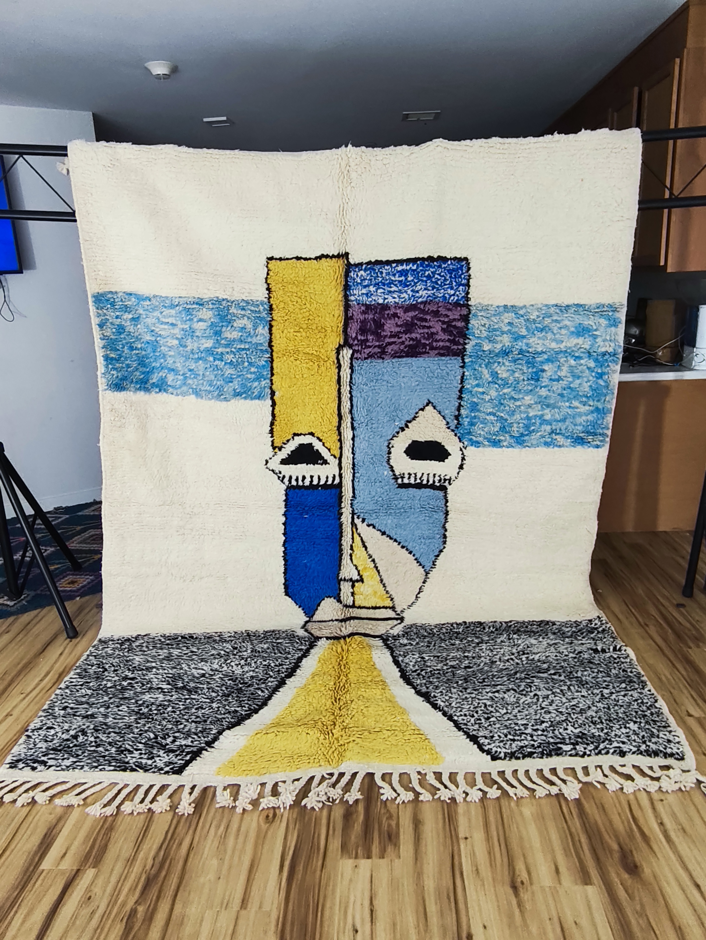 Fadwa — full hung studio view of Picasso-inspired cubist portrait rug in cobalt blue, mustard yellow and grey on ivory