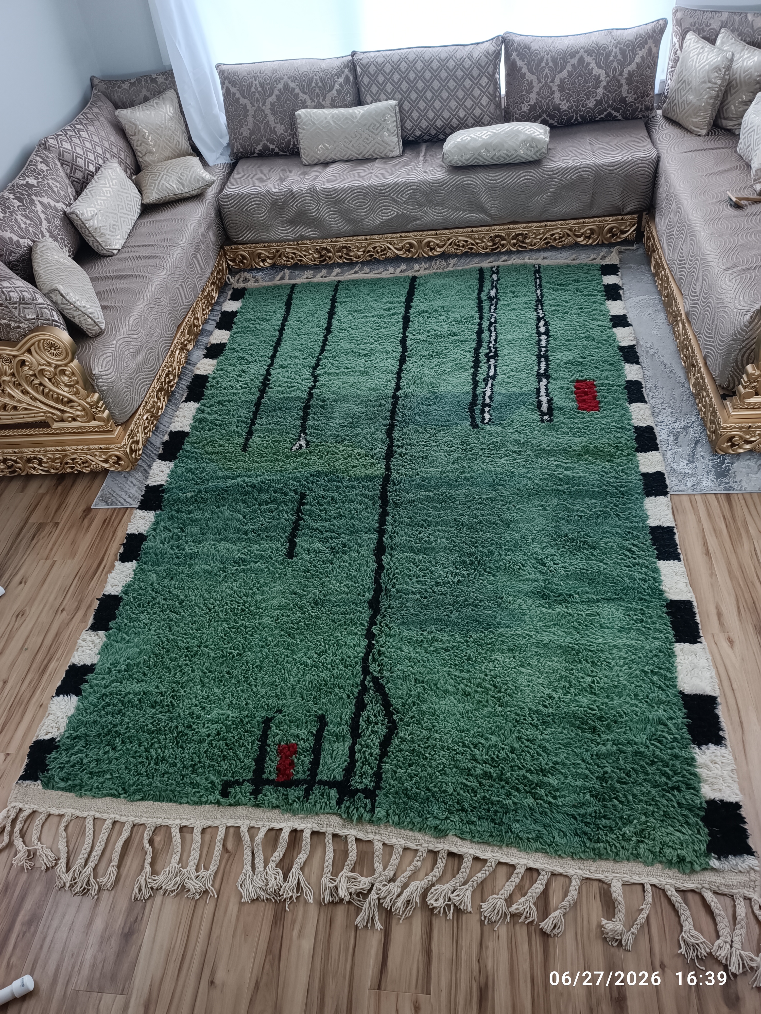 Forest green contemporary Moroccan rug with black free-form line art and black-and-white checkerboard border, in room setting