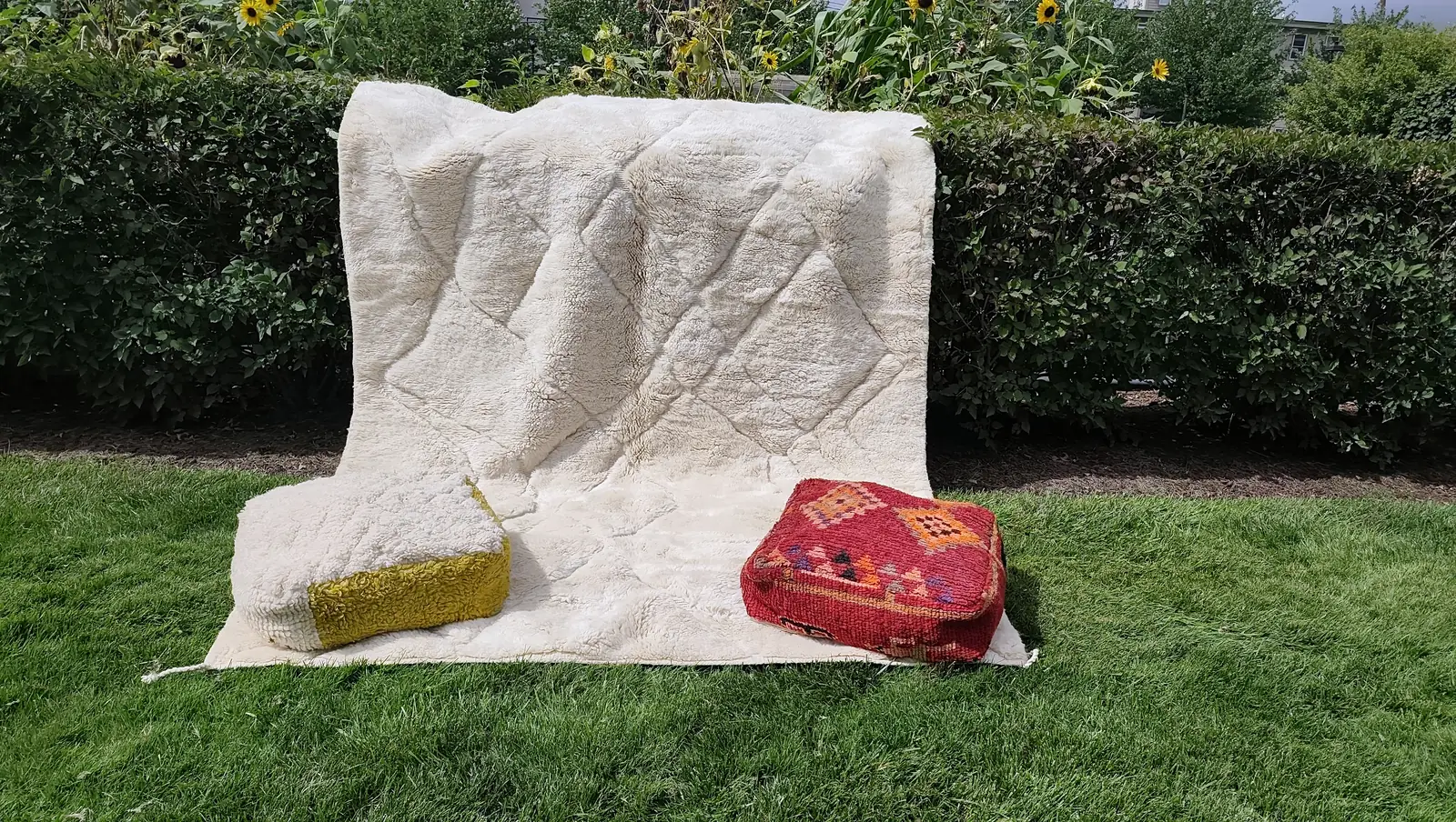Tafsut — draped over a park hedge so the pile falls in a long curve, poufs at the foot, view 4 of 18