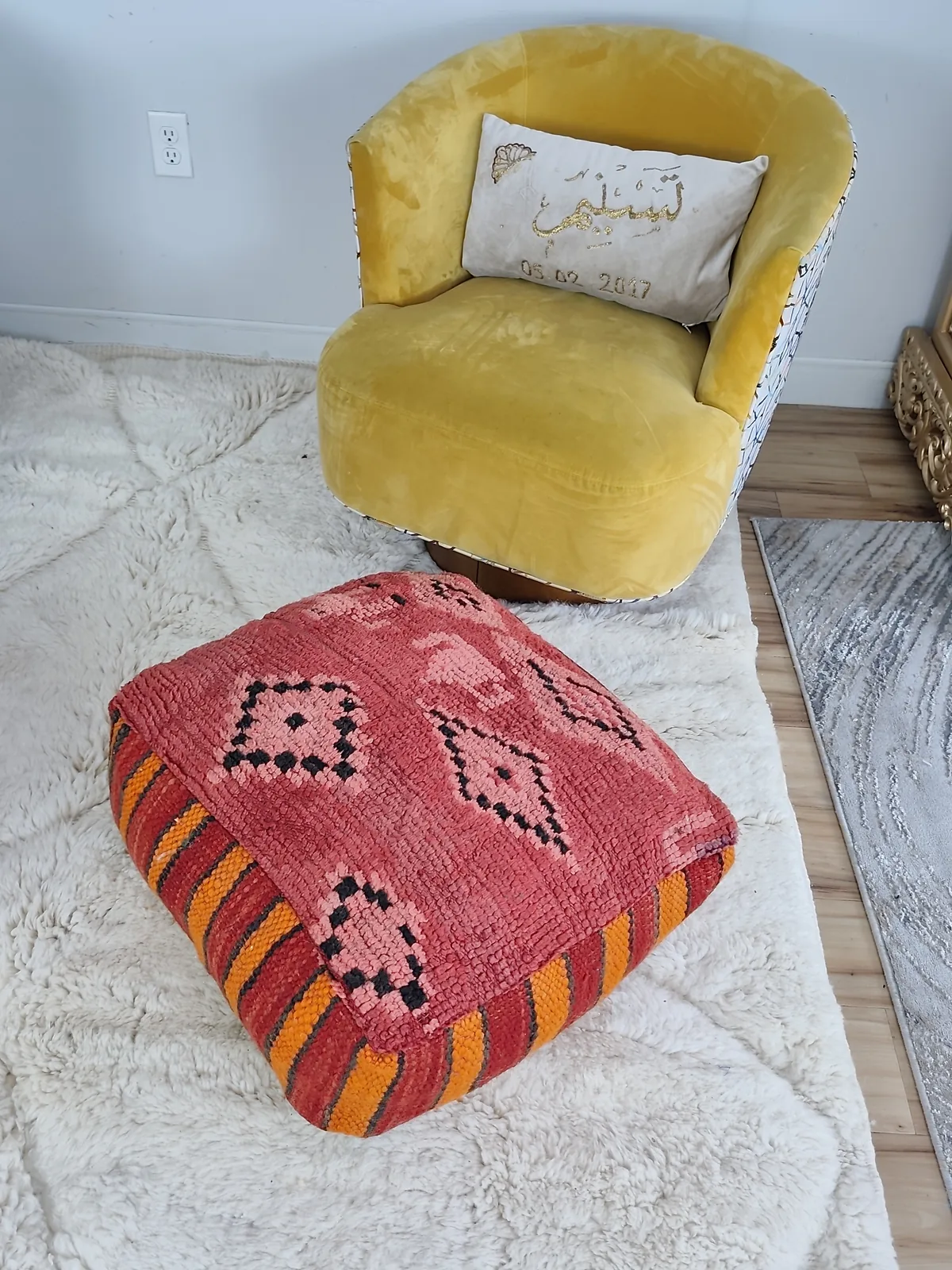 Damya — coral stripe pouf, styled beside a mustard armchair, view 6 of 7